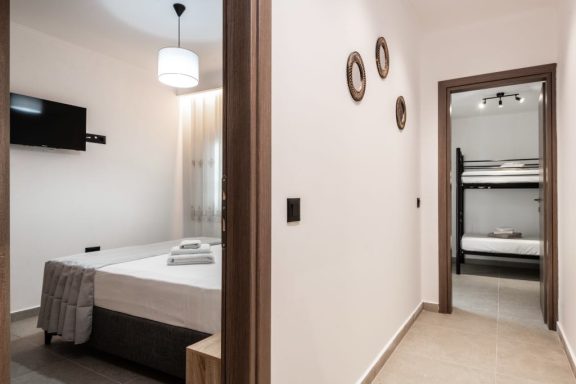 Modern interior of a hotel room featuring a double bed and a bunk bed in an adjoining area.