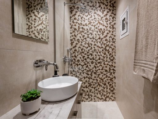 Modern bathroom featuring a round bowl sink, patterned wall, and a small potted plant.
