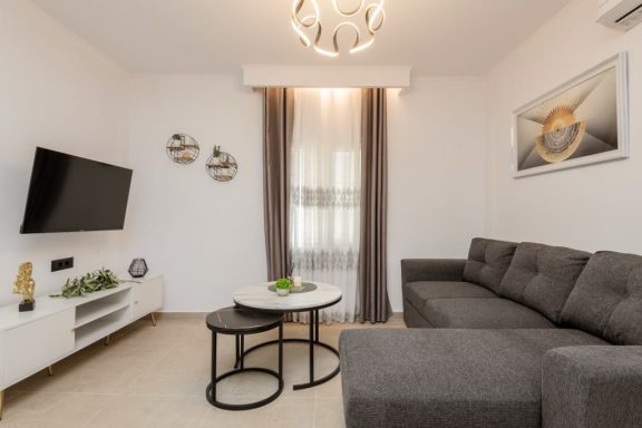 Modern living room featuring a grey sofa, coffee table, TV, and decorative wall art.