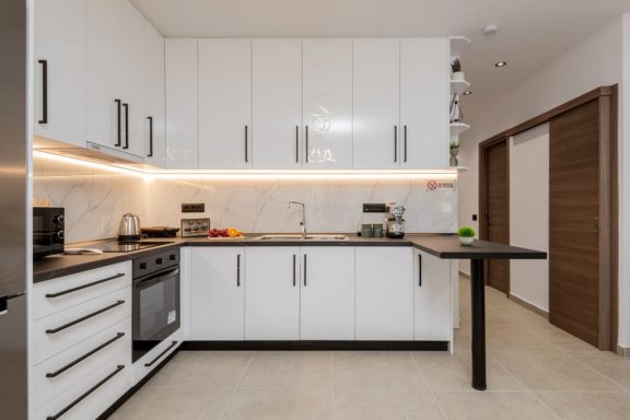 Modern kitchen with white cabinets, sleek countertops, and ambient lighting.