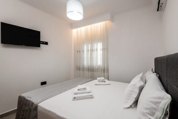 Modern bedroom featuring a double bed, soft lighting, and a wall-mounted TV.