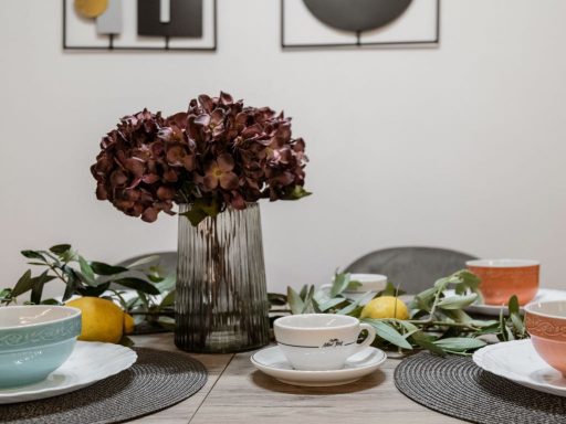 Table set with decorative flowers, tea cups, and citrus fruits.