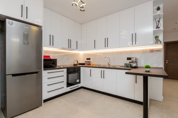 Modern kitchen with white cabinets, stainless steel appliances, and a small dining table.