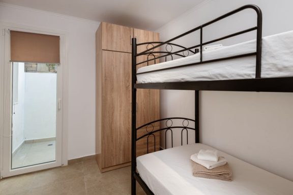 Bunk beds in a simple room with a wardrobe and a door leading outside.